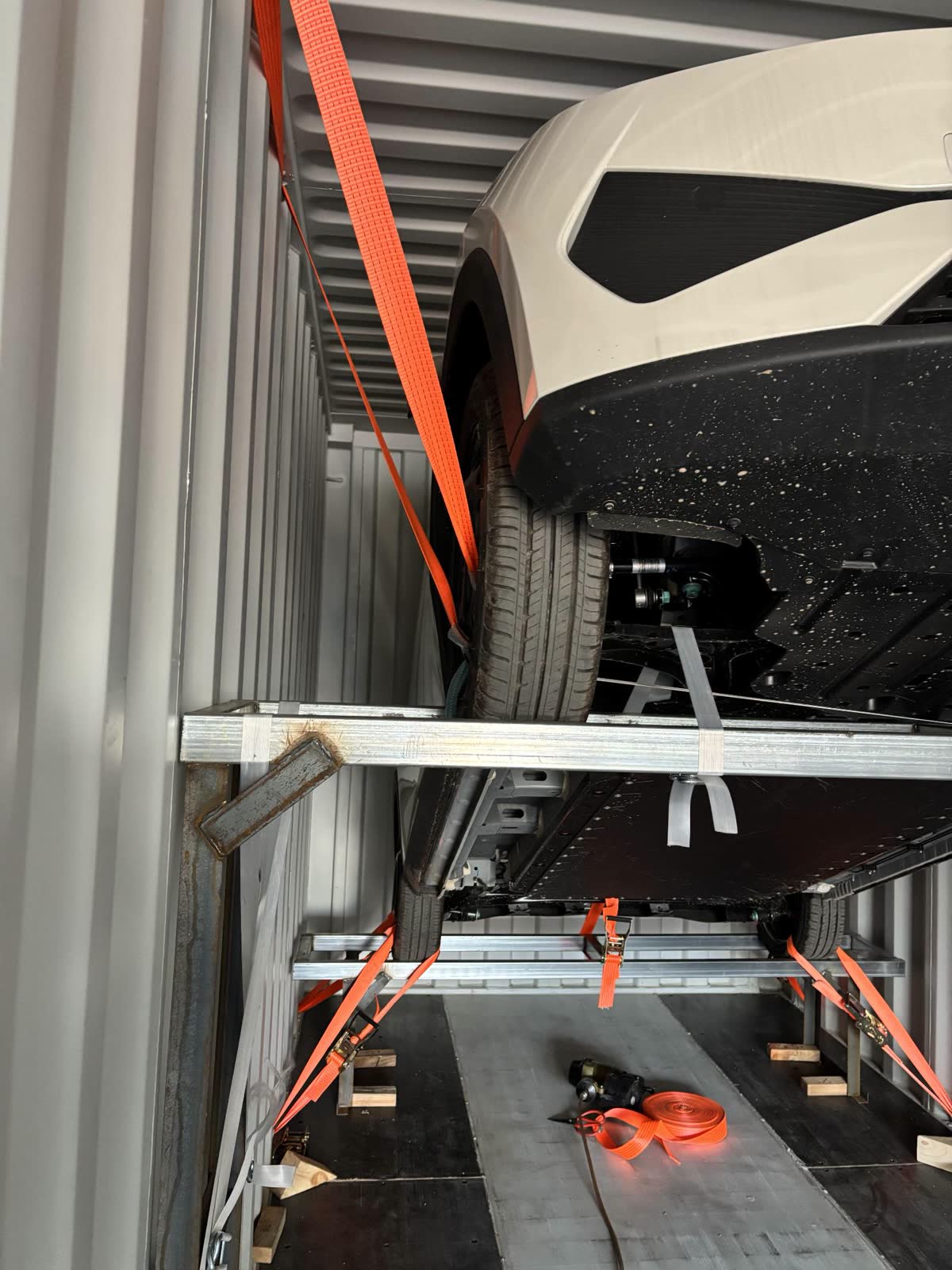 Car wheel lashed to a rack inside a 40ft container with webbing straps and timber bracing