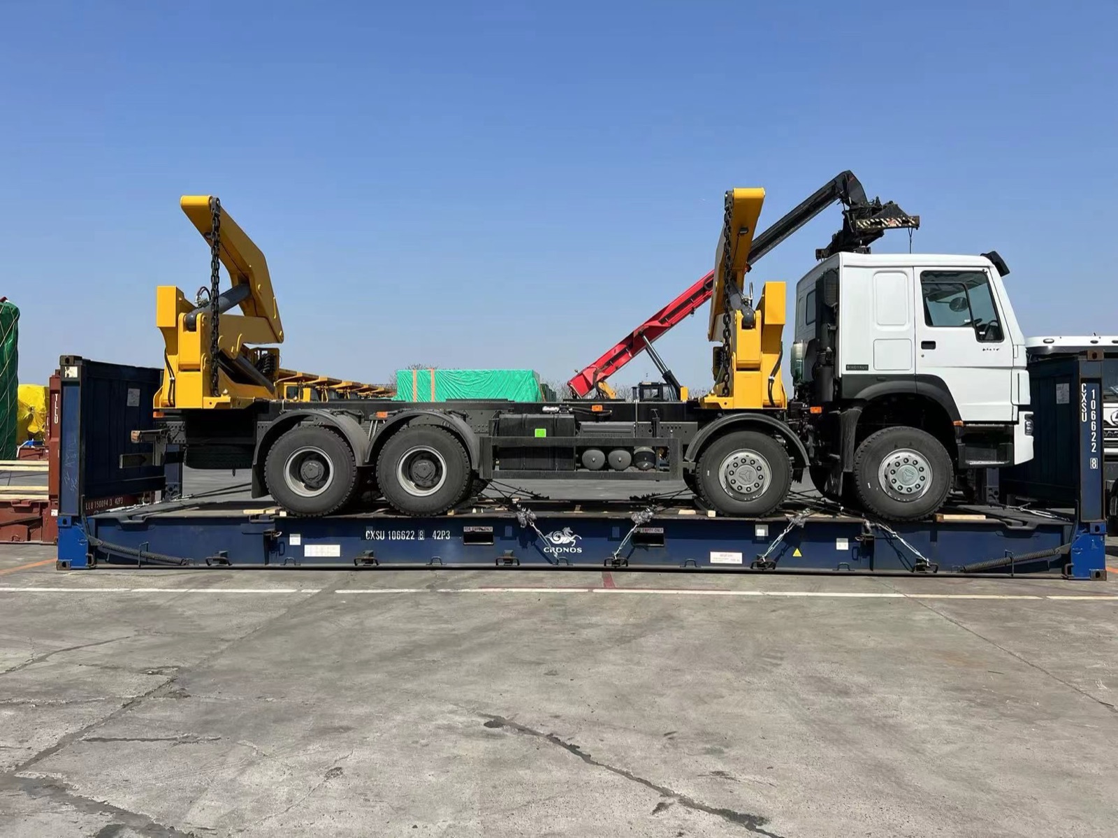 Six-axle truck with knuckle-boom loaders loaded whole on a flat rack, side view
