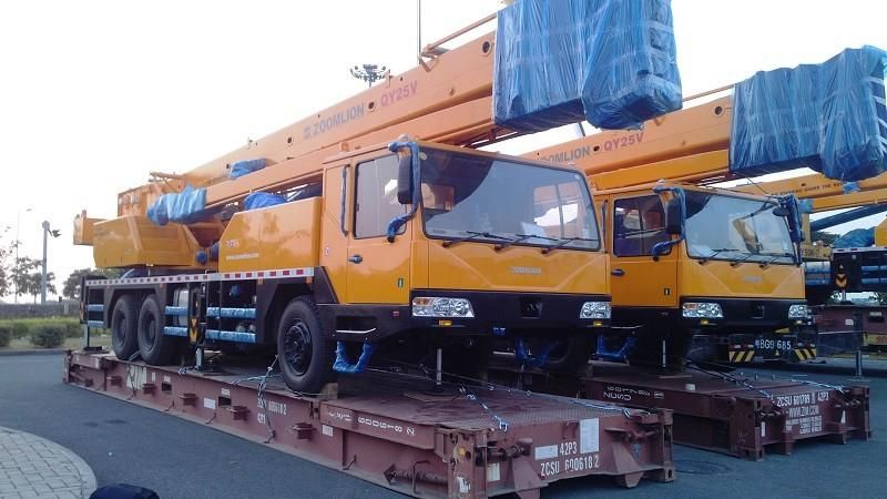 Two truck cranes loaded side by side on flat racks, angled view