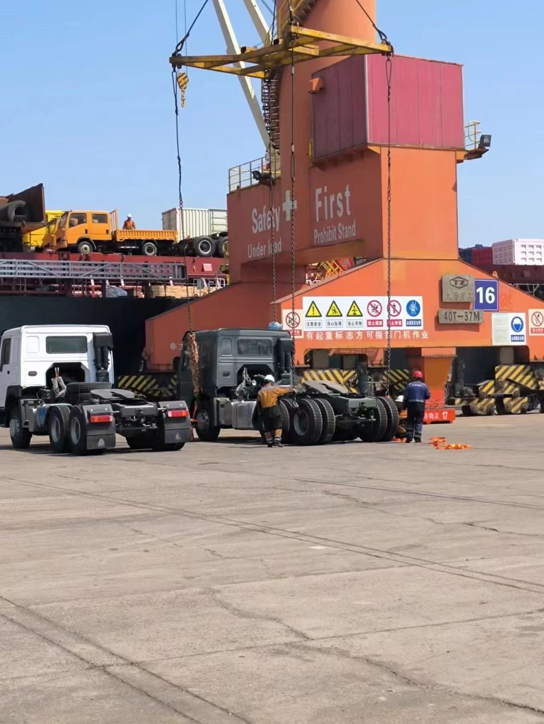Truck tractor heads prepared for lifting in the port yard under a gantry crane